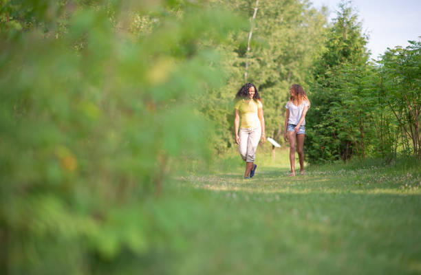 Young women hiking through a forest in a cool, natural environment with special equipment such as backpacks and hiking poles.