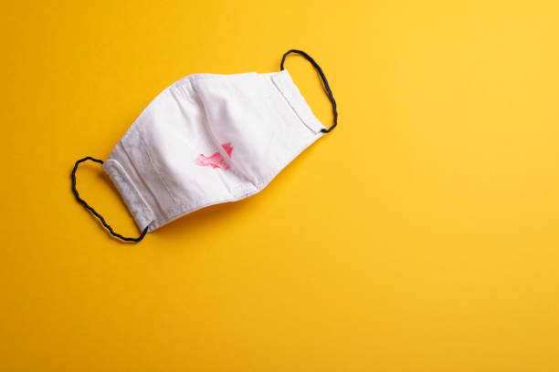 Facemask with red kiss mark on yellow. Love in a pandemic stock photo