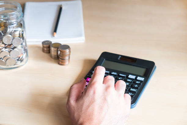 istock Selective focus at men hand using calculator with increase stack of money and glass jar on wooden desk. Personal financial saving concept for retirement or insurance. 1264327221