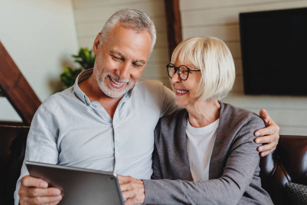 istock Senior couple using digital tablet in living room at home 1264327582