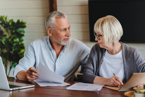 istock Aged couple signing and filling documents at home 1264328242
