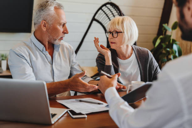 consulente finanziario che dà consigli di pensionamento alla vecchia coppia mentre litigano all'interno di casa - 401k retirement planning financial advisor foto e immagini stock