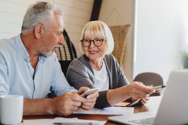 istock Beautiful senior business couple studying documents using laptop and smiling while working 1264328270
