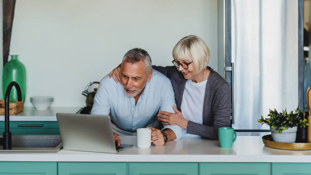 istock Portrait of two senior people using laptop at home kitchen 1264328290