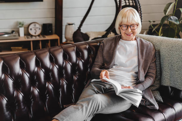 istock Senior woman in eyeglasses resting on sofa and reading book 1264328374