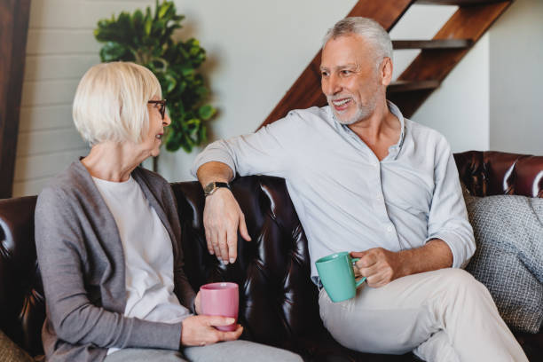 istock Happy mature couple or friends drinking coffee while resting on couch at home 1264328451