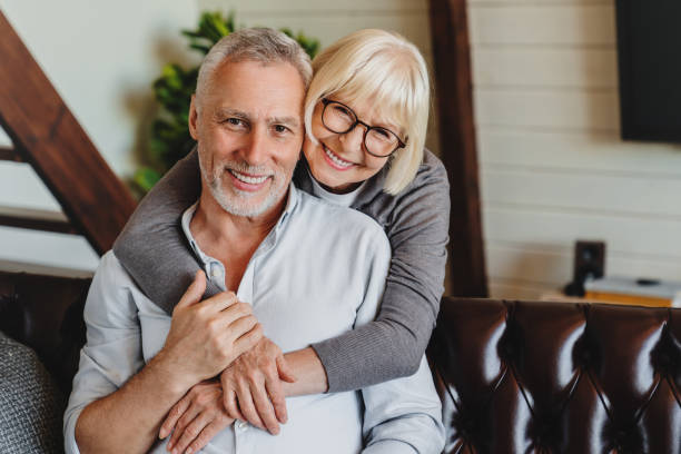 istock Senior couple sitting on a couch in living room while hugging 1264328467