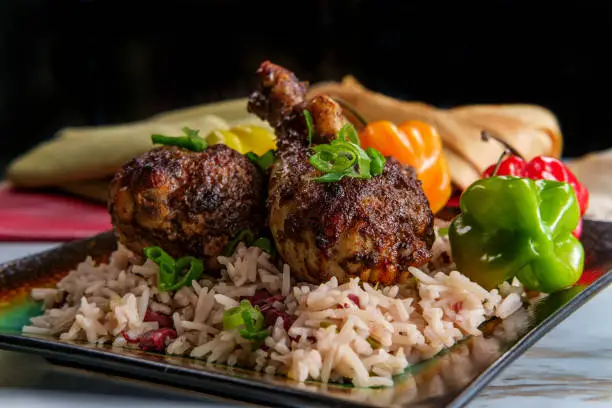 Authentic spicy Jamaican jerk chicken legs with scotch bonnet chili peppers served with coconut rice and peas