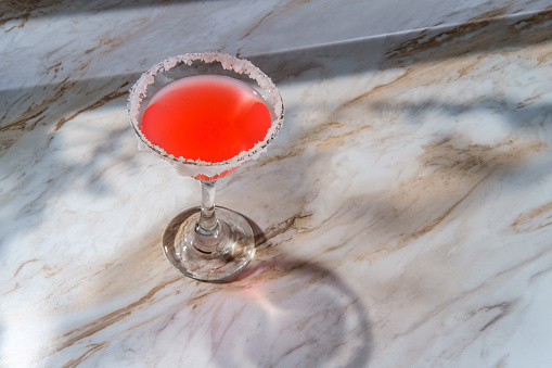 Pink martini with salted rim on marble kitchen table