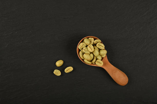 istock Spoon of unroasted raw green coffee on black 1264328931