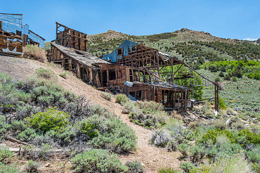 Abandoned ghost town house of wood in Californian desert with mountains at background