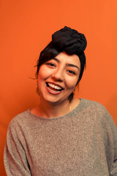 istock Young woman laughs, black bone on her head on orange background 1264330061