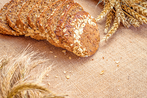 Loaf bread. Rye bakery with crusty loaves and crumbs. Fresh loaf of rustic traditional bread with wheat grain ear or spike plant on natural cotton background. Bio ingredients, very healthy seeds