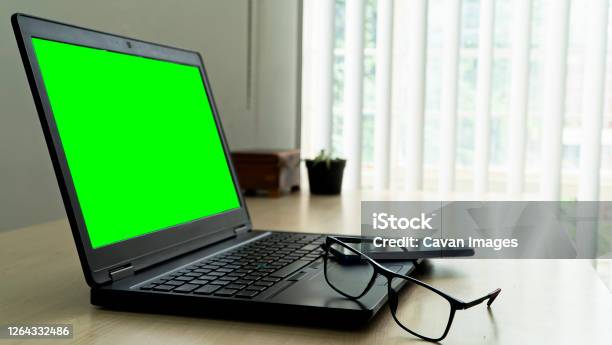Laptop On Wooden Desk With Green Screen Glasses And Smartphone W Stock Photo - Download Image Now
