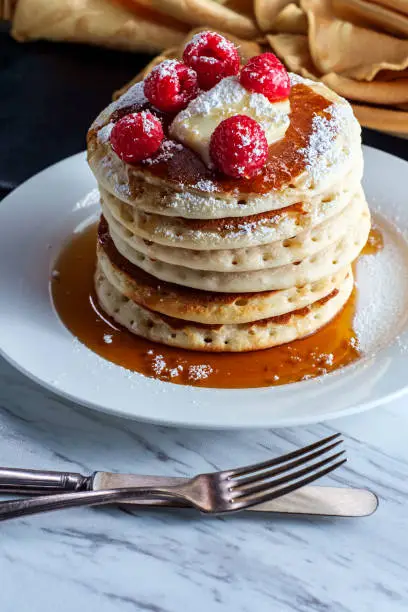 Pancakes with maple syrup powdered sugar raspberries and butter