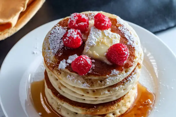 Pancakes with maple syrup powdered sugar raspberries and butter