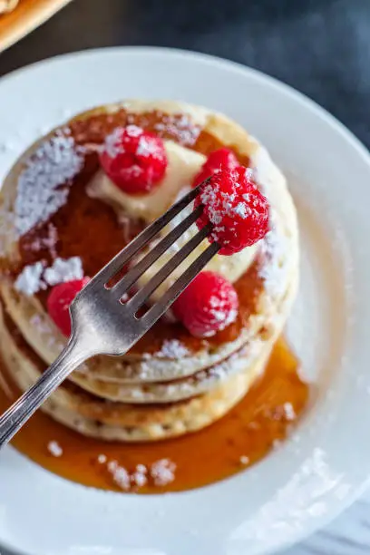 Pancakes with maple syrup powdered sugar raspberries and butter