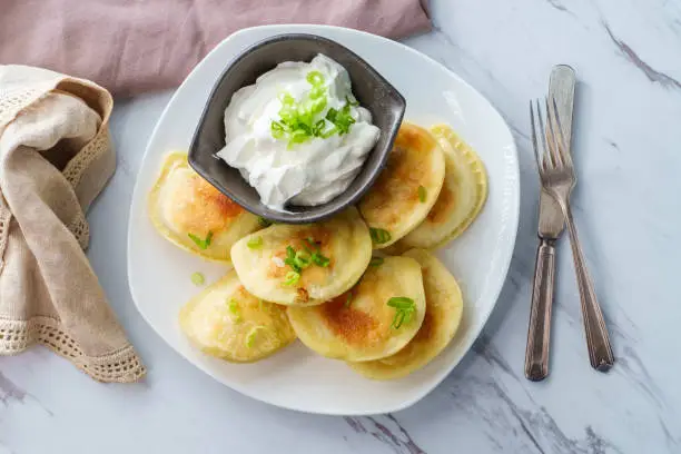 Delicious authentic Polish pierogies with chopped green onion and sour cream
