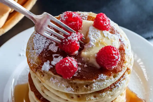 Pancakes with maple syrup powdered sugar raspberries and butter