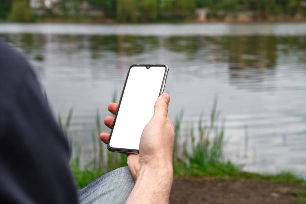 istock A man uses his smartphone on the shore of a pond 1264339519
