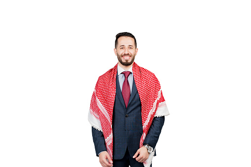 Handsome arabic businessman in suit and shemagh smiles on white blank background in studio. Business portrait of successful man