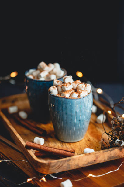 Hot chocolate with marshmallows and cinnamon in blue ceramic cups on a table. The concept of cozy holidays and New Year.