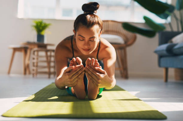 Make sure you stretch enough Shot of a young woman practicing yoga at home touching toes stock pictures, royalty-free photos & images