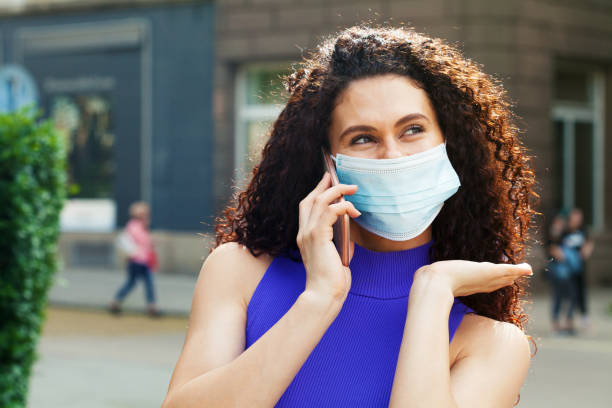 istock Young woman with a protective face mask talking on the phone 1264346424