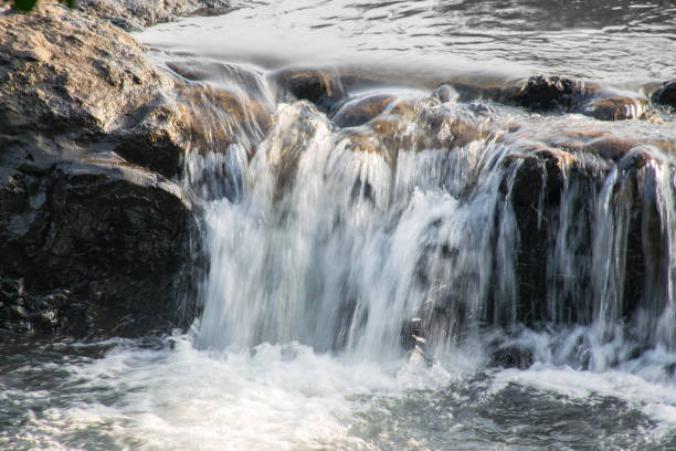 Panoramic view of a small waterfall with silky water flowing over rocks located in rural part of Maharashtra, India