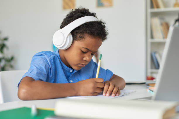 istock Concentrated black boy with curly hair listening to teacher advice and solving task while studying with tutor online 1264348865