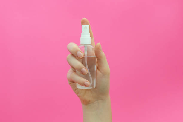 istock Woman holds alcohol-based hand-washing spray on pink background. 1264348877