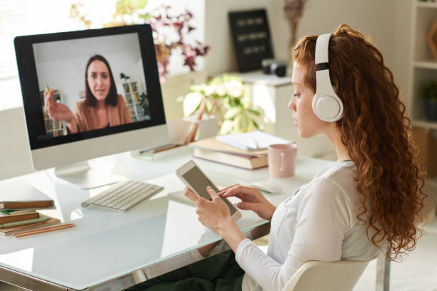istock Concentrated redhead student girl in headphones using tablet while studying with tutor online 1264349073