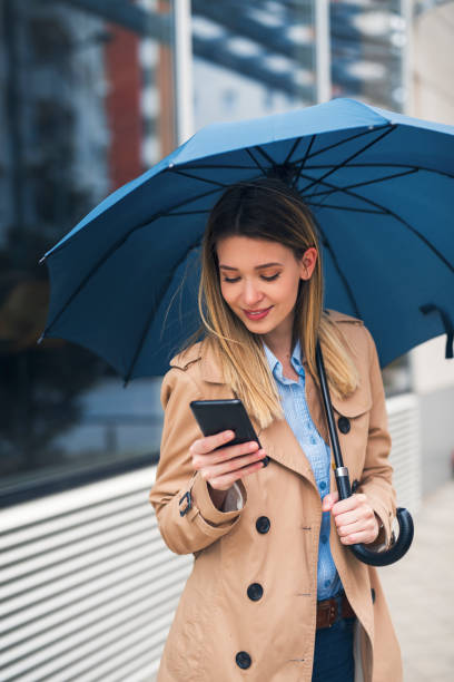 istock Charming lady with umbrella and cellphone 1264352485