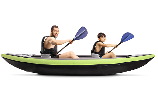 Young man and a boy with safety vests sitting in a kayak with paddles isolated on white background