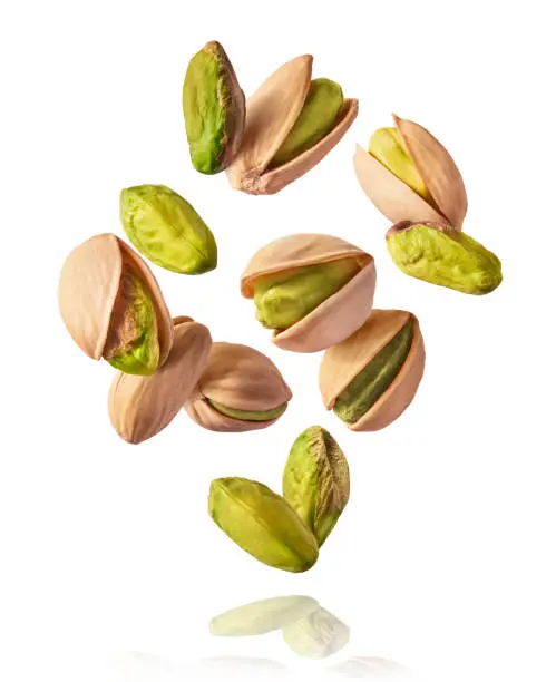 Flying in air fresh raw whole and cracked pistachios  isolated on white background. High resolution image