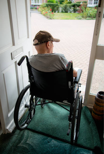 彼の家の開いた出入り口から外を見ている車椅子の老人。イギリスハンプシャー州 - housebound ストックフォトと画像