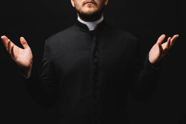 istock cropped view of priest with outstretched hands isolated on black 1264355263