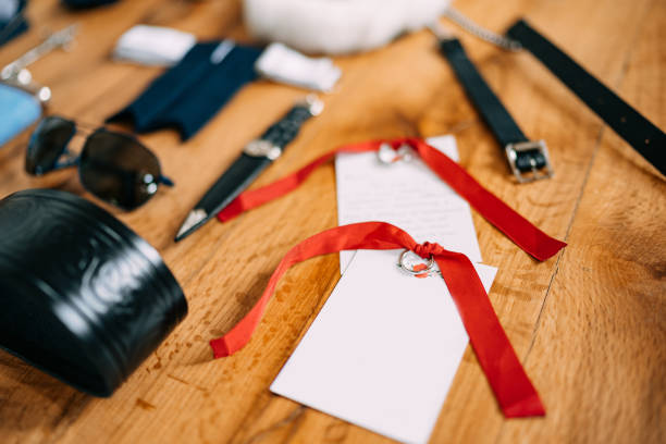 istock Blank sheets for the wedding vow text on a wooden smooth surface with accessories for the groom sunglasses, belt and knife. 1264356130