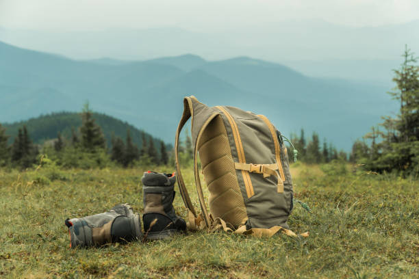 istock Khaki color boots and backpack standing on a grass on top of a mountain hill. 1264356213