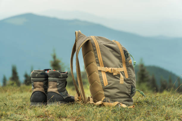 istock Khaki color boots and backpack standing on a grass on top of a mountain hill. 1264356216
