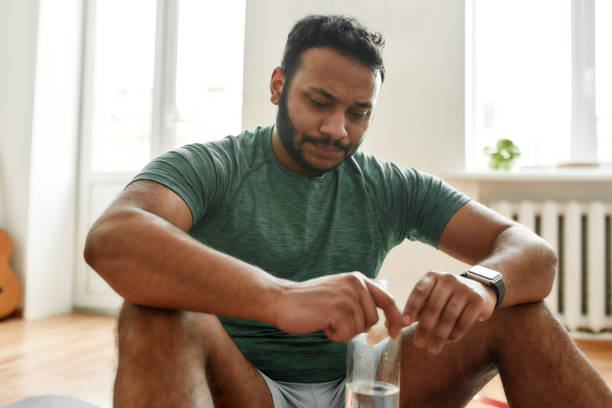 istock Exhausted. Young tired man looking down dissatisfied, holding water bottle in his hands while resting after training workout at home. Sport, healthy lifestyle 1264356298