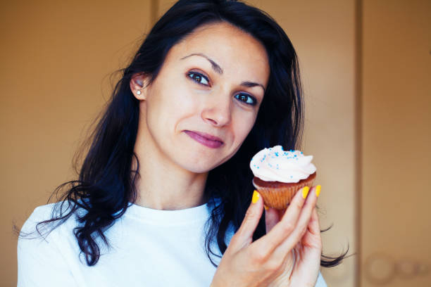 istock Young woman eating a cupcake 1264357210