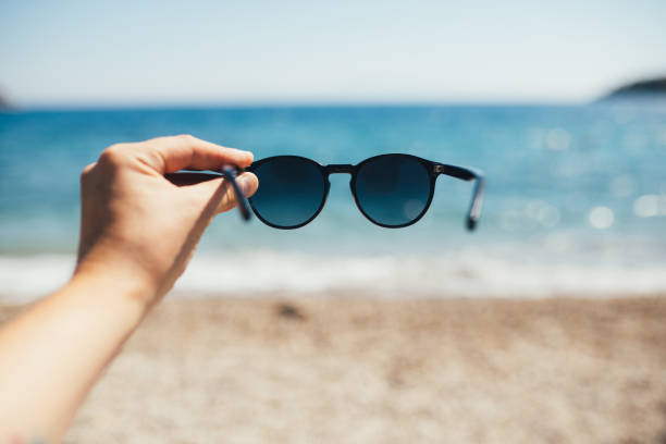 istock Man holding sunglasses at the beach 1264358188