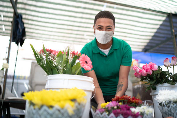 portrait of a young florist working in a street market - with face mask - florist flower market flower store imagens e fotografias de stock