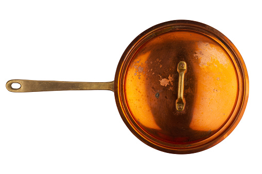 top view closeup of old cooking pan with copper lid and metallic handle isolated on white background