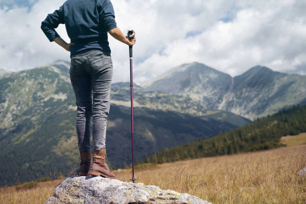 rear view of woman with hiking stick looking at the mountains - valley storm thunderstorm mountain imagens e fotografias de stock