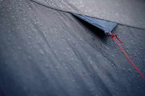 anchoring red rope on tent with drops of rain stock photo