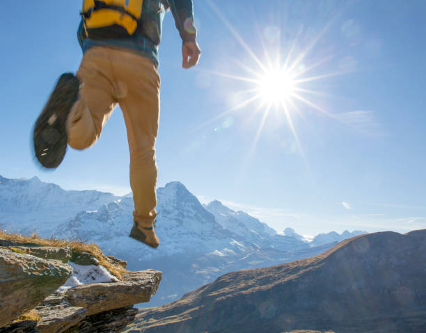 istock Hiker leaps onto sunny mountain ledge 1264360523