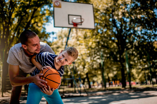 istock Cute blond boy practicing basketball with his coach 1264362408
