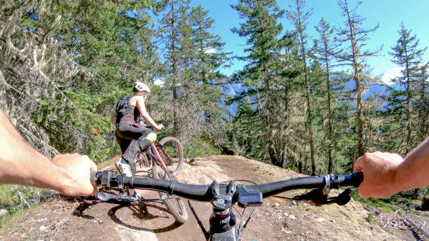 istock Female mountain biker rides along forested path 1264364159